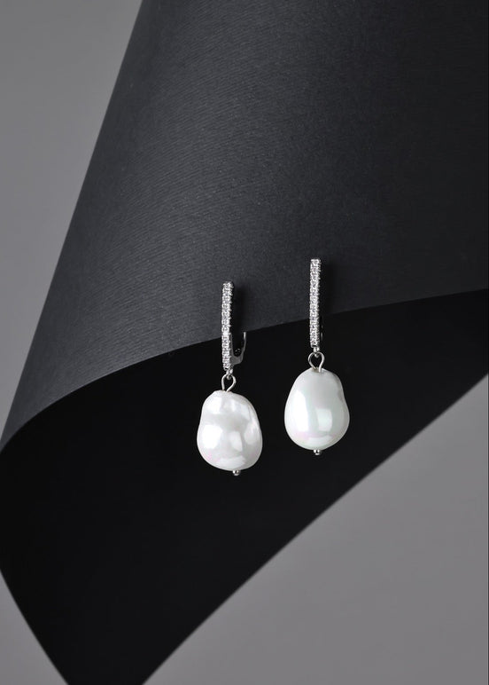 Pearl earrings on a black and gray background