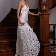 Woman in a white dress with floral details standing on a staircase.
