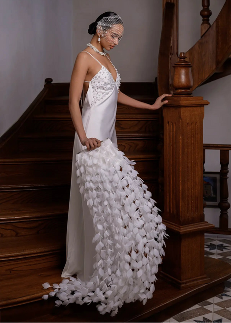 Woman in a white dress with floral details standing on a staircase.