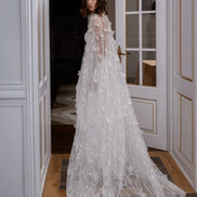 Woman in a white lace wedding dress standing in a doorway.