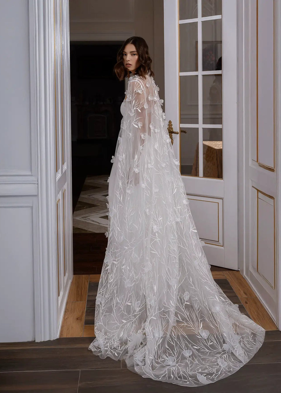 Woman in a white lace wedding dress standing in a doorway.