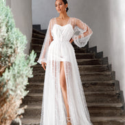 Woman in a white wedding dress standing on stone steps with greenery.