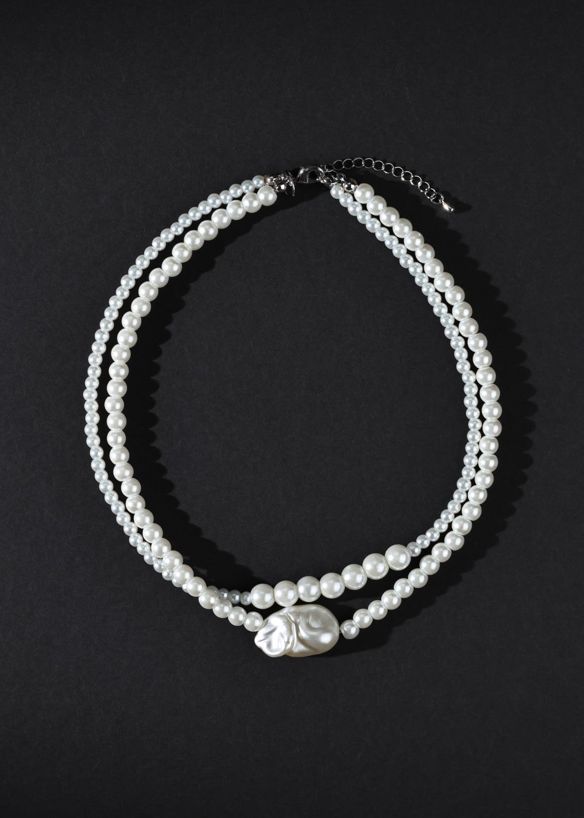 Two pearl necklaces on a black background