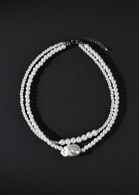 Two pearl necklaces on a black background
