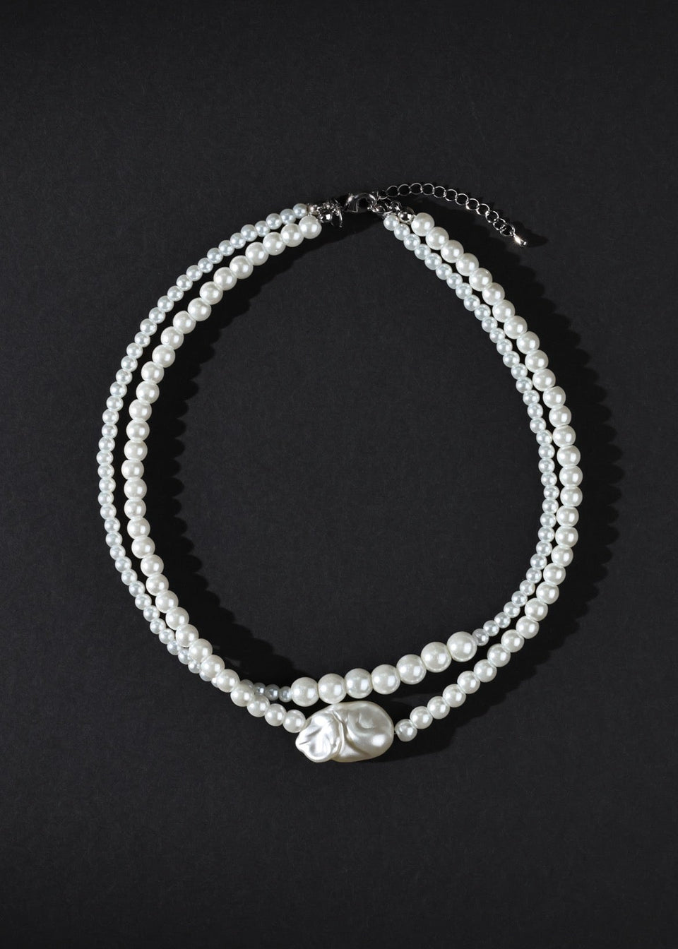 Two pearl necklaces on a black background