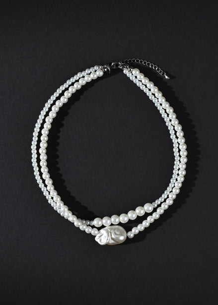 Two pearl necklaces on a black background