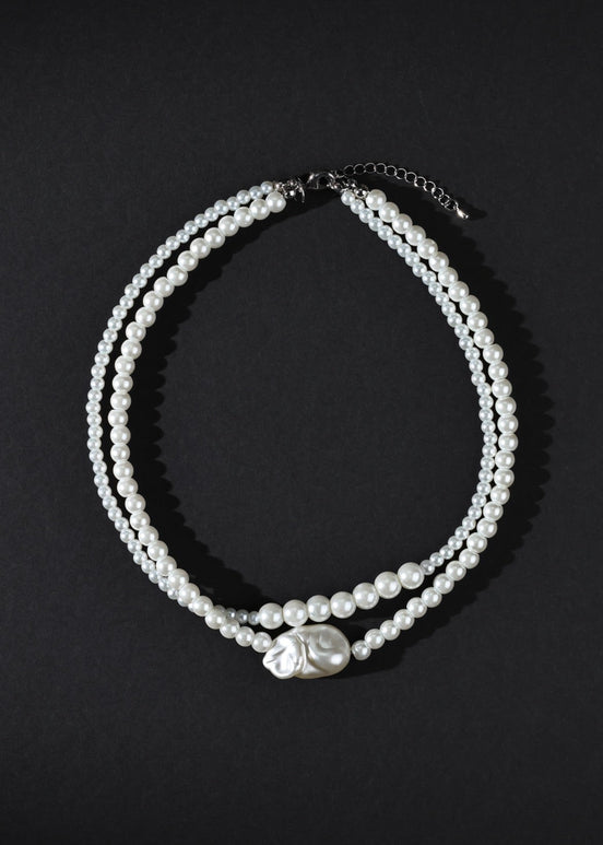 Two pearl necklaces on a black background