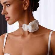 Woman wearing a white floral necklace with a plain background