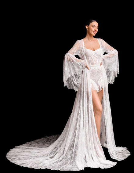 Woman wearing a white lace robe over a matching outfit on a black background