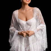 Woman wearing a sheer white lace robe against a black background