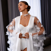 Woman wearing a white outfit with floral details against a neutral background