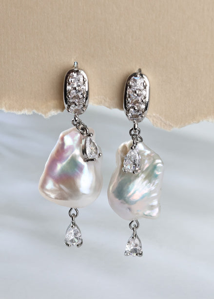 Pearl and crystal earrings on a textured beige and white background