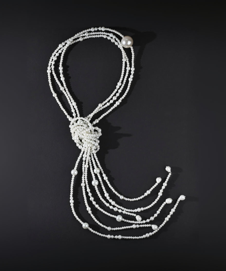 Pearl necklace with a knot on a black background