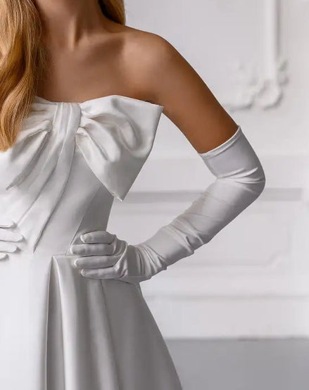 White off-shoulder dress with long gloves on a plain background