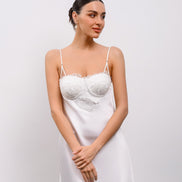 Woman wearing a white lace nightgown against a plain background