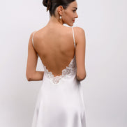 Woman wearing a white lace nightgown against a plain background