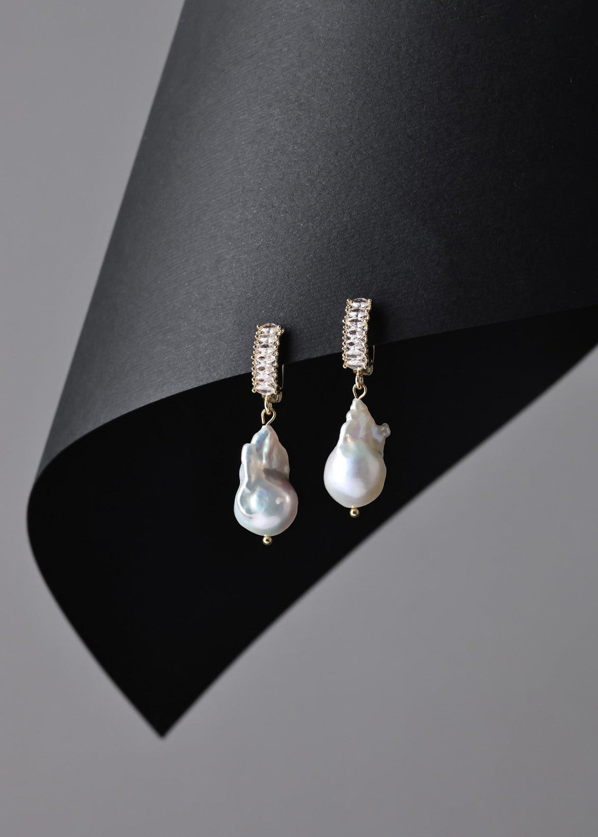 Pearl earrings with gold accents on a black and gray background