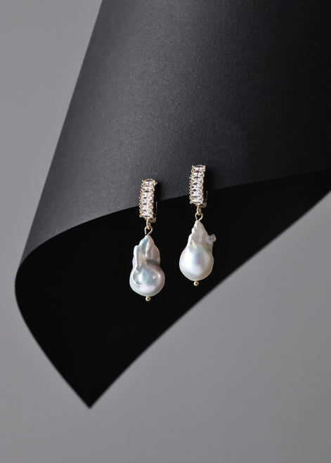 Pearl earrings with gold accents on a black and gray background