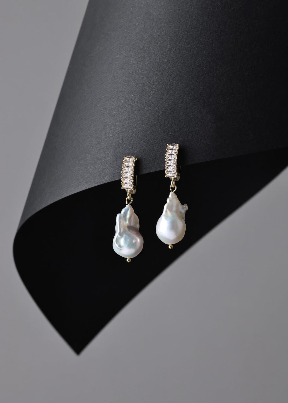 Pearl earrings with gold accents on a black and gray background