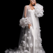 Woman in a white wedding dress with floral details against a black background