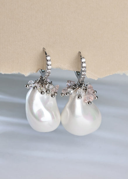 Pearl earrings with silver and pink accents on a light blue and beige background