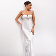 Woman wearing a white satin slip dress against a plain background