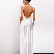 Woman wearing a white dress with a low back design against a plain background