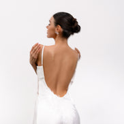 Woman wearing a white dress with an open back on a light gray background