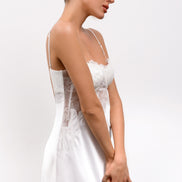 Woman wearing a white dress with thin straps on a plain background