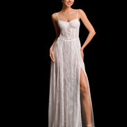 Woman wearing a white lace evening gown with a high slit on a black background