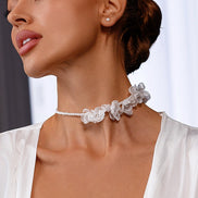 Close-up of a woman wearing a delicate floral necklace with a blurred background