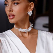 Woman wearing a white dress with floral jewelry against a blurred background